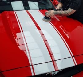 A member of Perauto's team polishing a red Ford Mustang bonnet