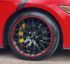 Red Alloygator protecting a gloss black Mustang wheel from kerb damage