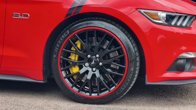 Red Alloygator protecting a gloss black Mustang wheel from kerb damage